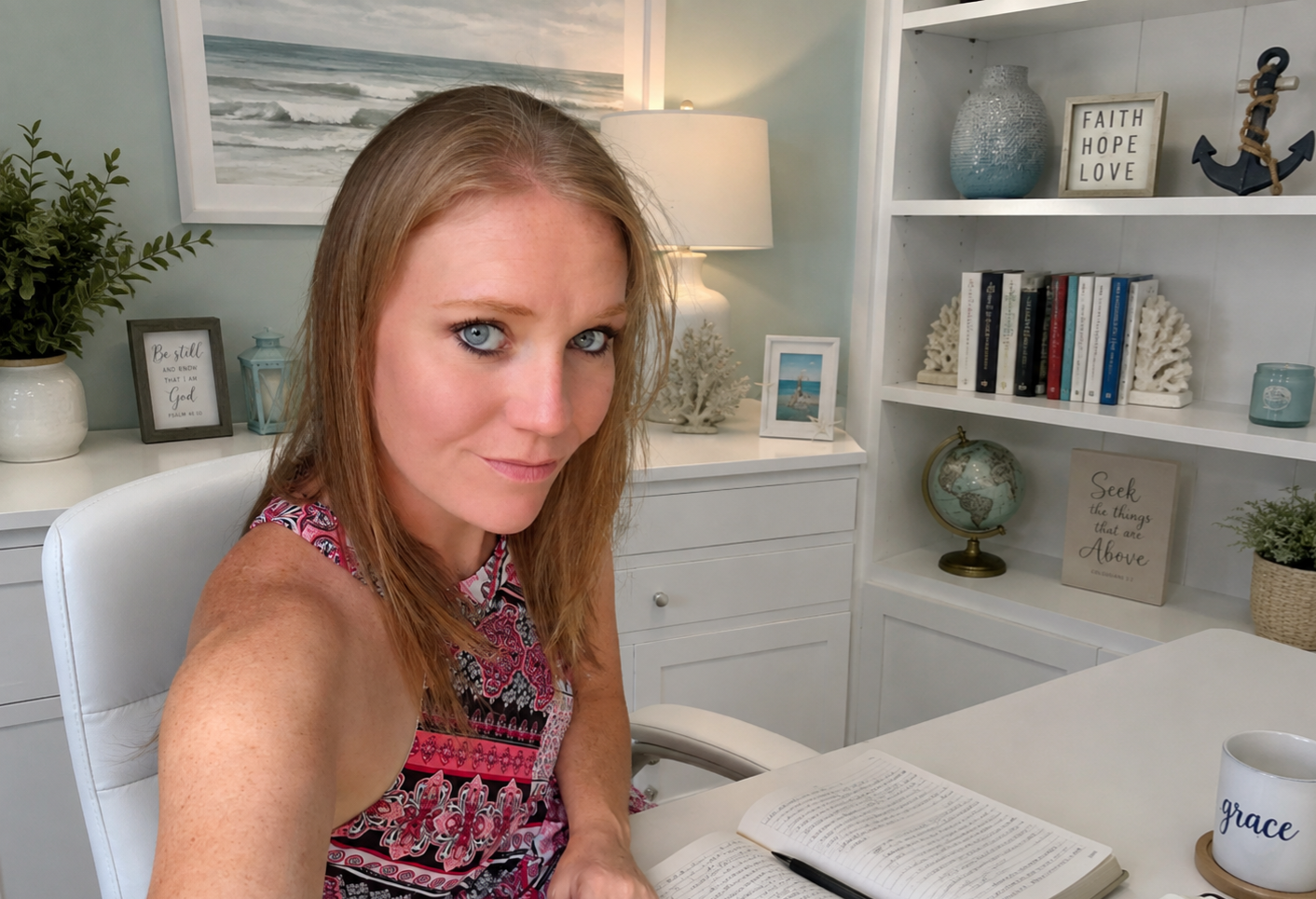 Woman sitting at a desk studying an open Bible in soft natural light